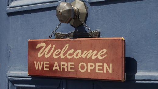 un cartello con su scritto welcome we are open appeso ad una porta
